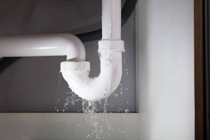 Plumbing leak repair Singapore — water leaking from cracked white PVC under-sink pipe, emergency plumber